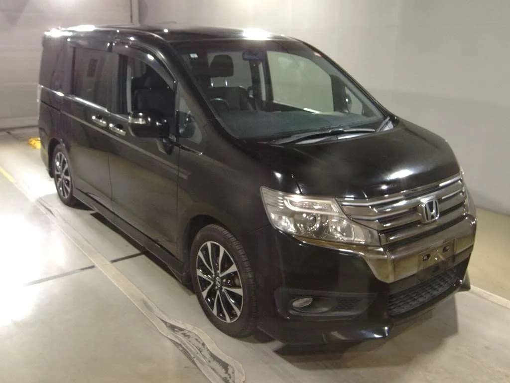 2013 Honda Step Wagon Spada in black - front-right 3/4 view with chrome bar grille, projector headlights, window visors, and two-tone diamond-cut alloy wheels