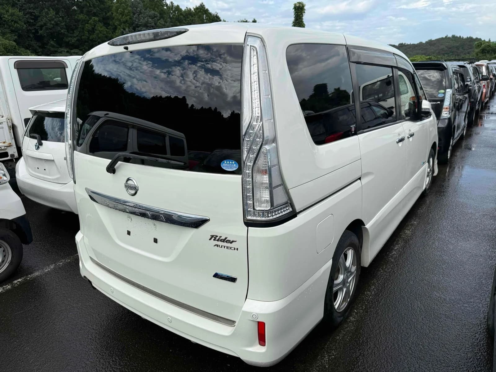 2014 Nissan Serena Rider S-Hybrid MPV in pearl white - rear-right 3/4 view with tall LED tail lights, chrome SERENA tailgate strip, Rider Autech badge, and window visors